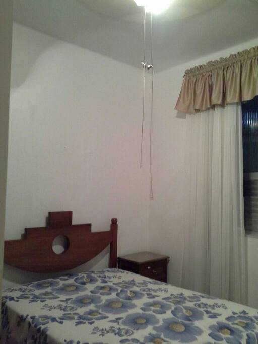 Quarto com cama de casal, ar condicionado split, ventilador de teto e guarda roupas