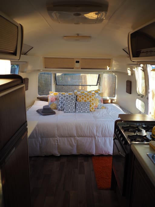 Full bed in the front with quality linens and assorted pillows.