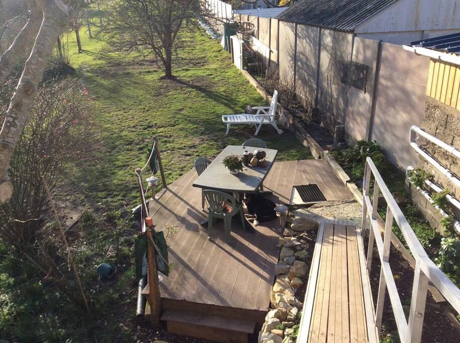 terrasse avec table de jardin, chaises, coin pelouse. verdure et calme