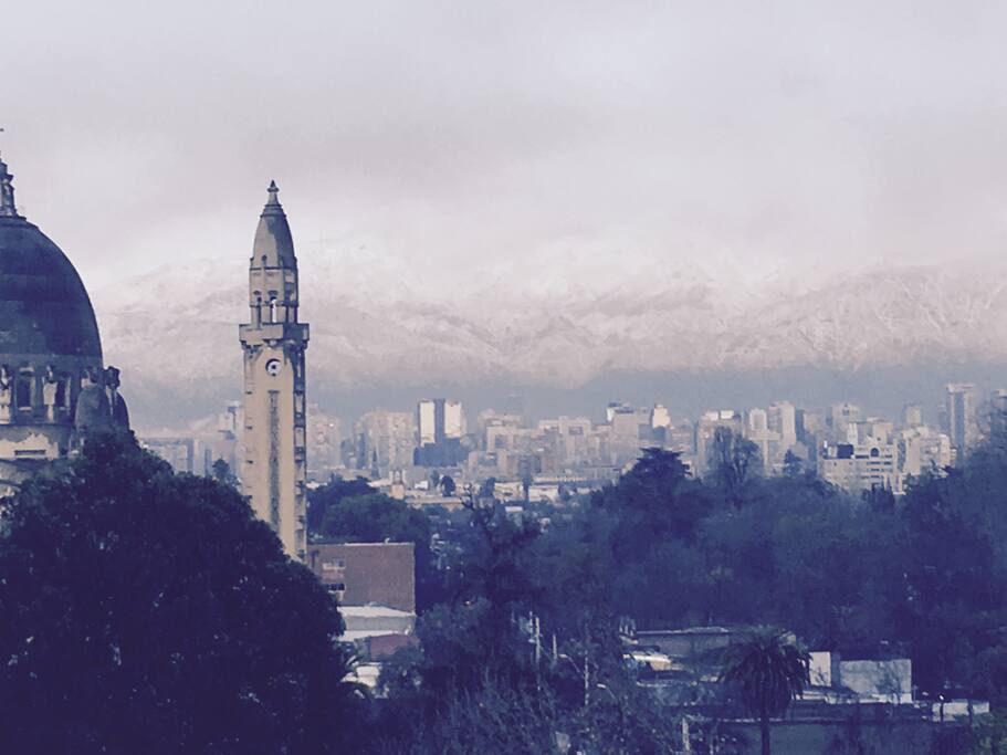 aparece de fondo la cordillera de Los Andes , y frente a mi departamento la capilla de Lourdes y al costado el gran y cultural parque quinta normal ( está foto fue tomada en el mes de julio )