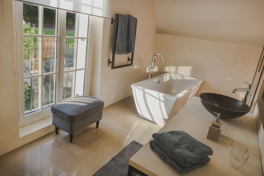 La salle de bain avec baignoire et douche