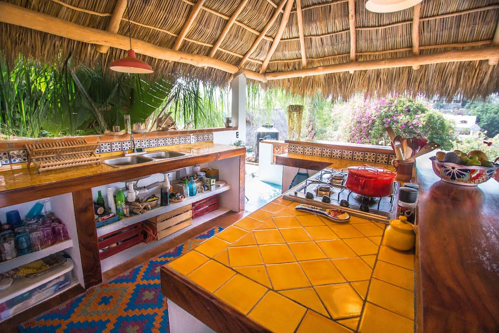 large outdoor kitchen under a palapa (palm frond) roof