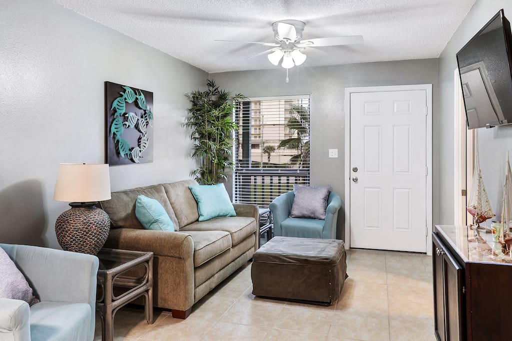 Living area includes sleeper sofa, 2 chairs, and large wall-mounted TV
