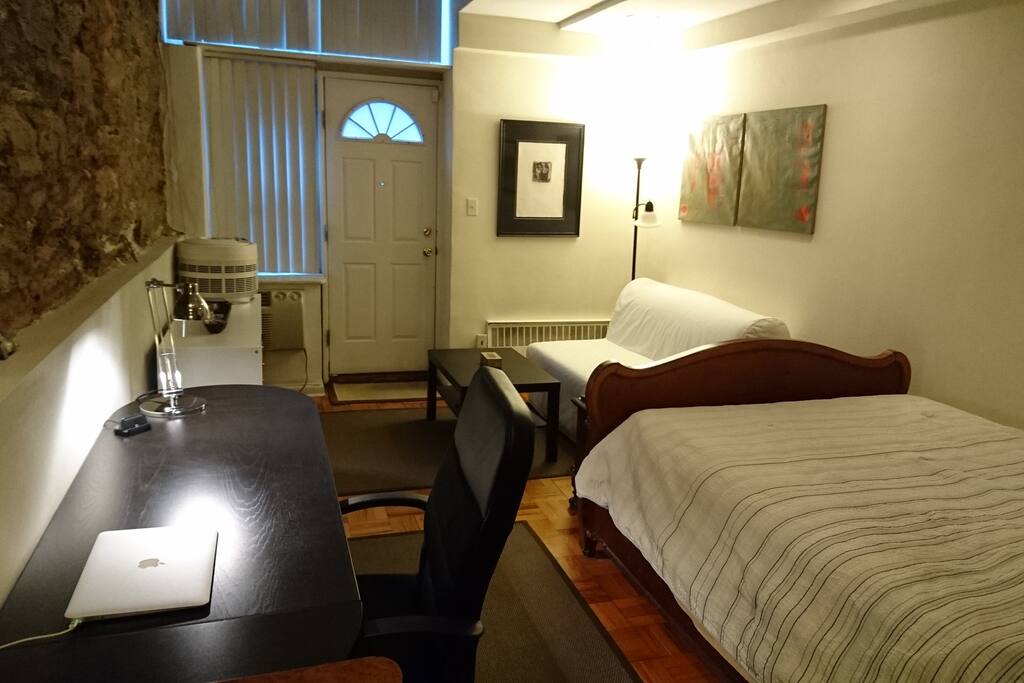 This view is looking toward private entry door opening to sidewalk. Window and door face south. Futon bed for one located at end of bed. A/C under window. Self controlled electric heat.