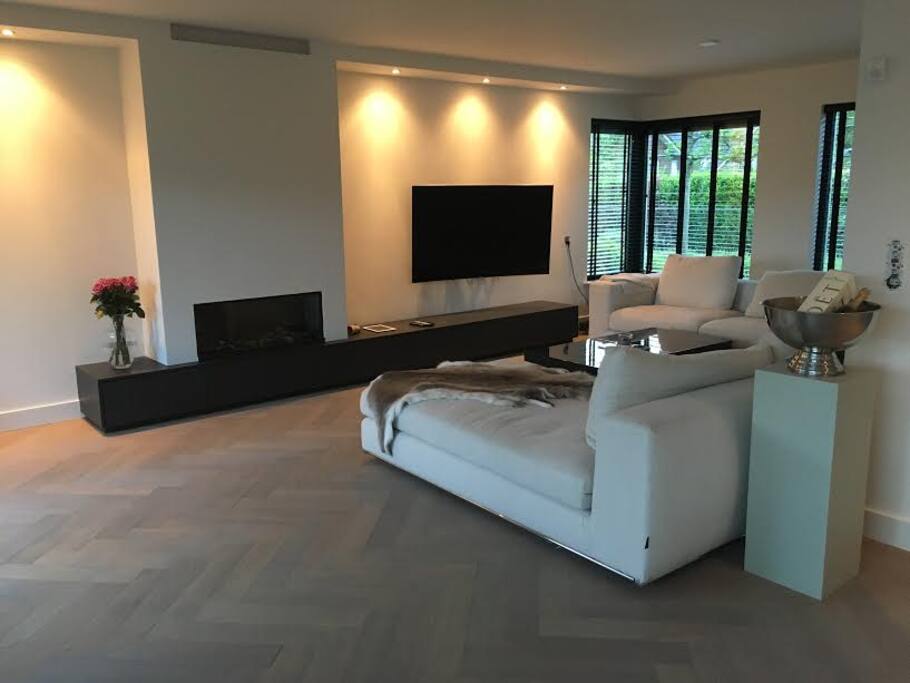 Luxe woonkamer met 7 persoons bank, 65inch TV en sfeervolle gashaard