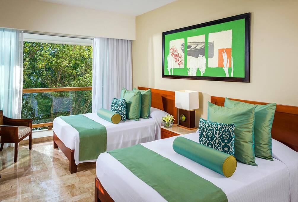 The Bedroom with plush beds, beautiful bright windows, chairs, and dresser with drawers