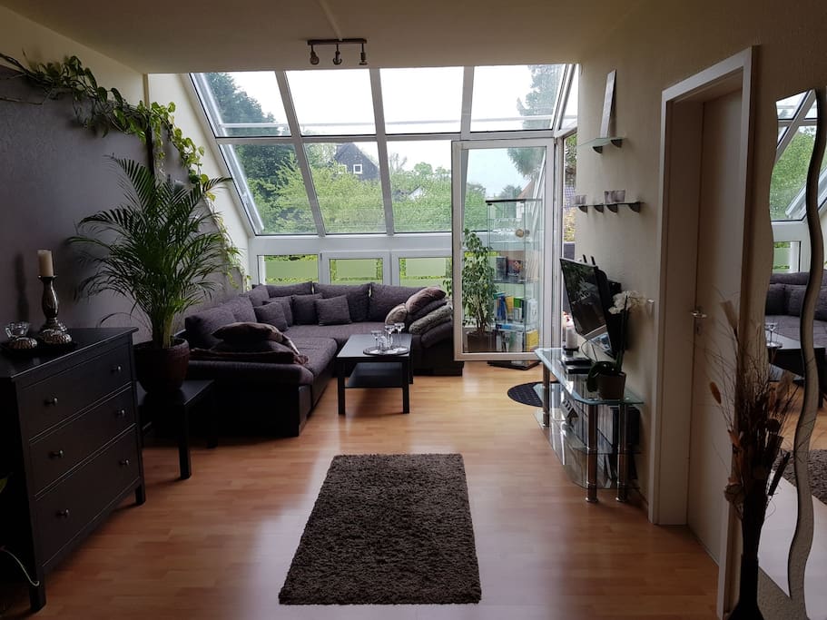 Wohnzimmer mit Schlafsofa für maximal 2 Personen, Platz für ein Zustellbett für 1 Person, offenen Küchenbereich, Zugang zur Terrasse, Fernseher, DVD-Player und Wintergarten mit einer grossen Glasfront...