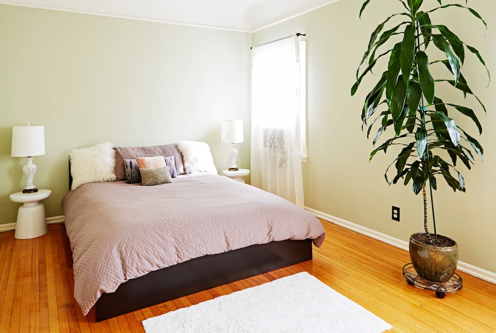 Very large bedroom with lots of light, and a comfortable cozy bed with luxurious sheets.