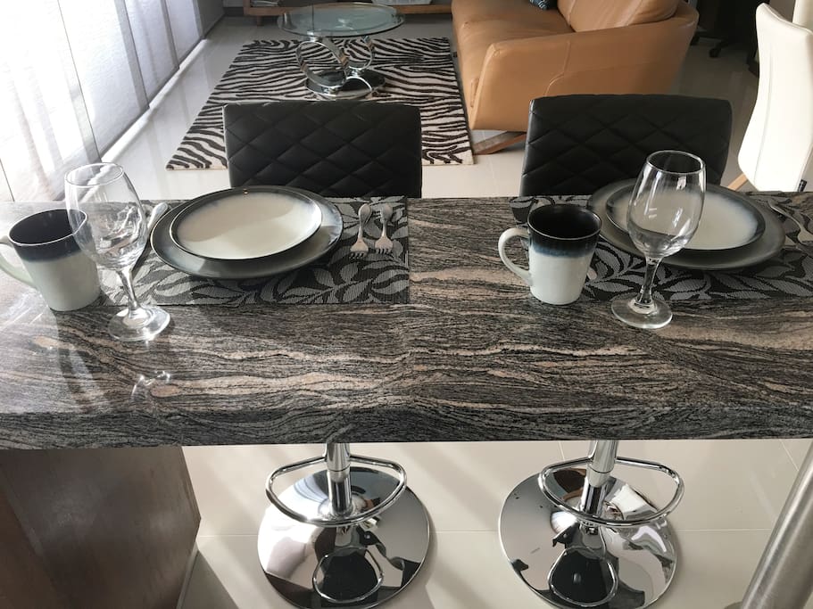 Bar set up for a meal! Full dish set, wine glasses. Lovely black and white stone/marble counters.