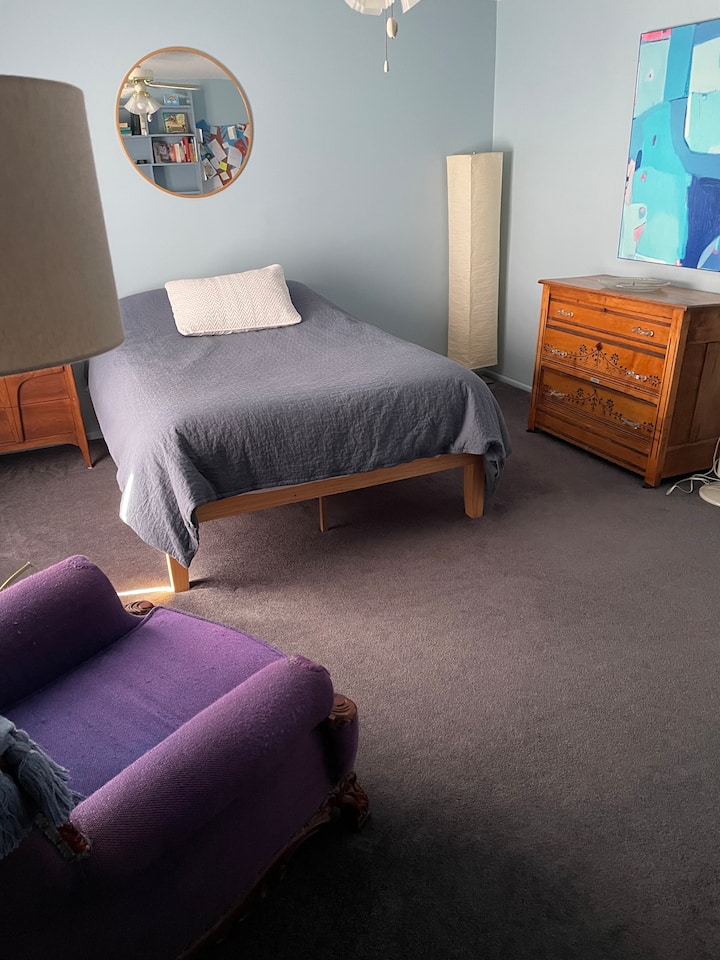Habitación de huéspedes de Airbnb.  Cama de tamaño completo. 
Silla morada famosa.