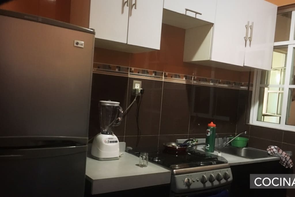 Cocina integral equipada con barra y dos bancos