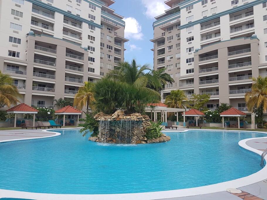 pool area with cabanas and lounge chairs and gazebo. Stand-up shower for rinsing off, near pool