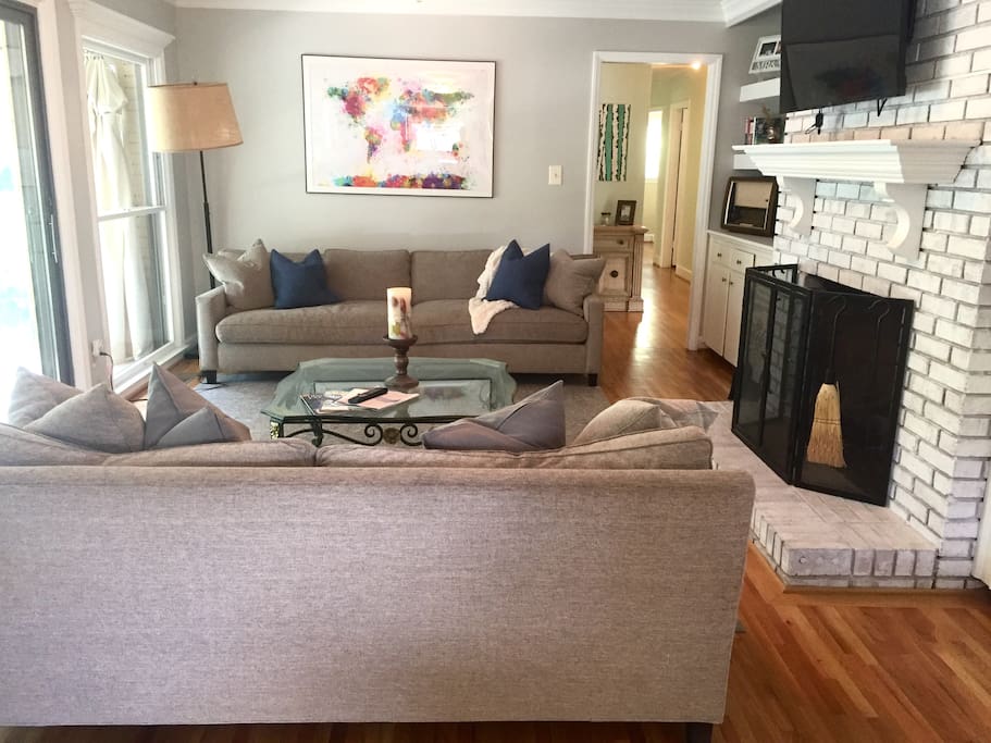 Main living room with TV, books, and a view of the backyard area through the sunroom.