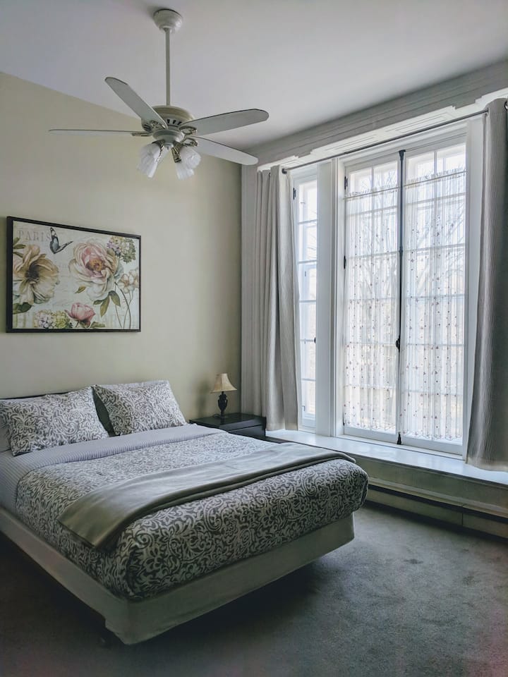 חדר שינה מרווח עם תקרה גבוהה וחלון תמונות ענק הפונה לפארק אספלנד (הצד המערבי).