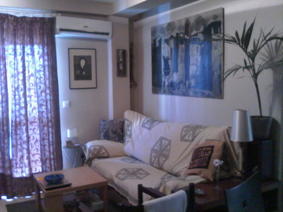 Sala de estar con sofá tres plazas, butaca y A/A.