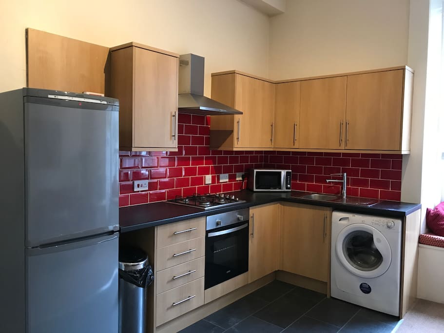 Kitchen with a gas hob, electric oven, large fridge freezer and a washing machine.