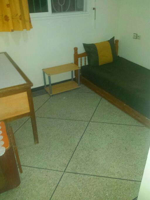 Une petite chambre qui se compose d'un bureau.,un placard, un lit et une comode