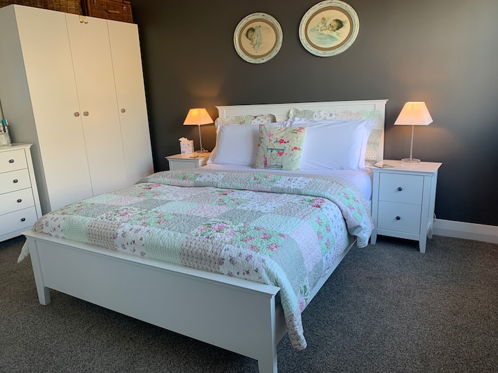 Comfortable Queen sized bed made up with crisp cotton sheets in a sweet charming bedroom. Ample storage for your bits and bobs with wardrobe, drawers as well as bedside table reading lights. 