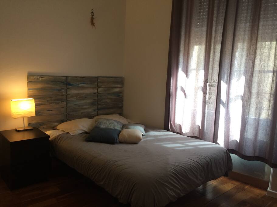 Chambre avec lit double et parquet ancien.