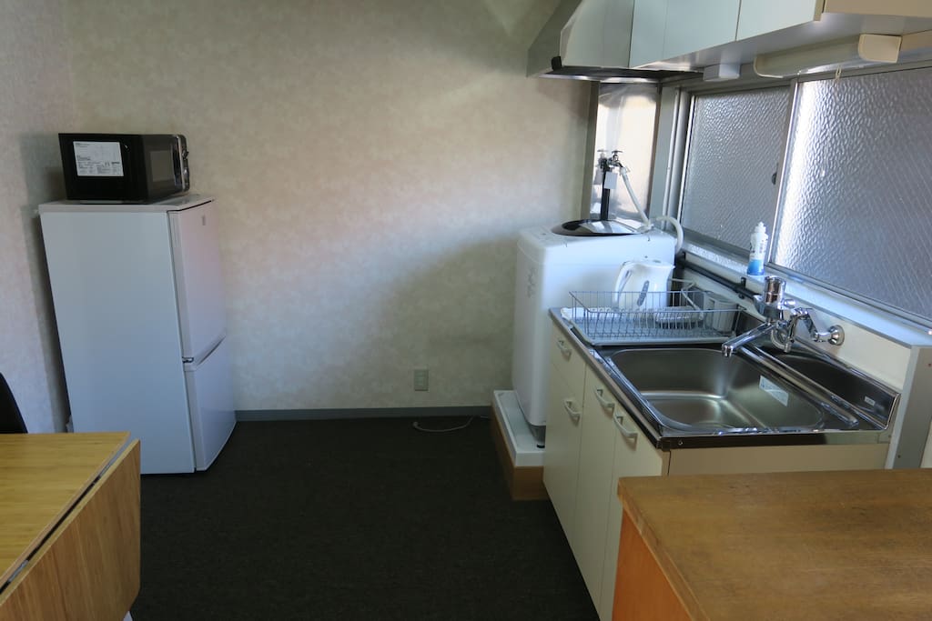 Kitchen with a microwave, a fridge, a kitcinette, and a laundry machine. A bamboo table is good for a small party..