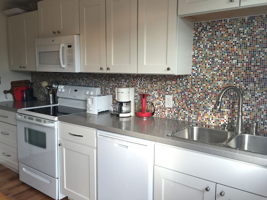The kitchen has lots of dishes, glasses, cutlery, and cookware