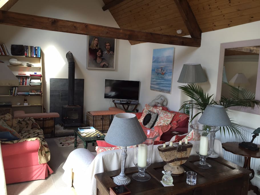 Open plan living area with wood burning stove, TV, 3 sofas.