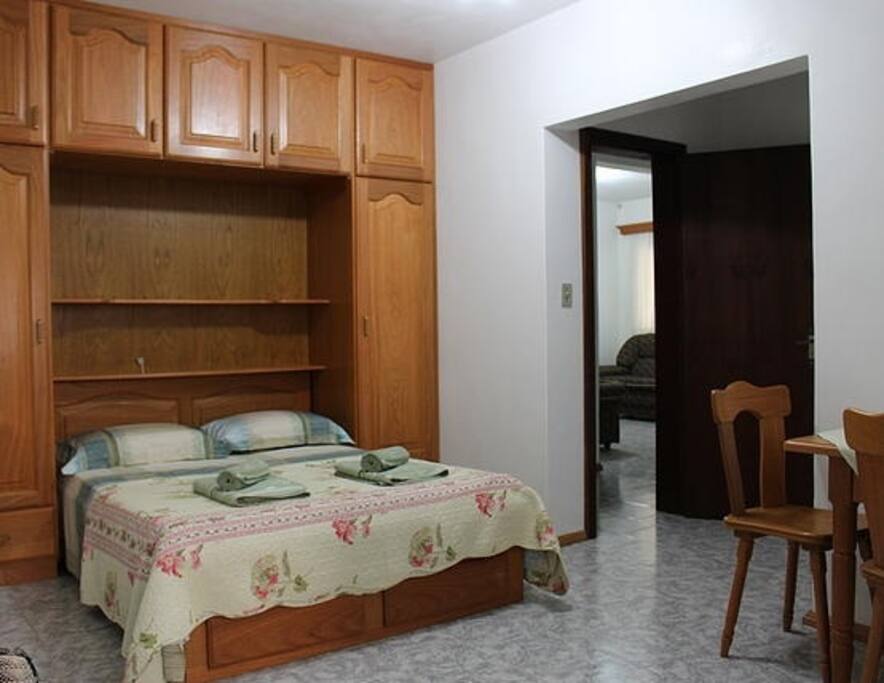 Quarto com cama de casal, possui ainda uma mesa pequena e um sofá cama.