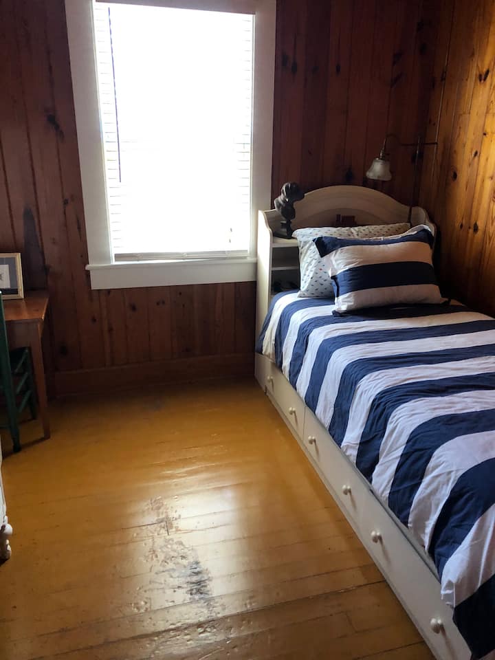 Quarto do meio com cama de solteiro; as roupas podem ser guardadas em gavetas embaixo ou no armário que está no quarto
