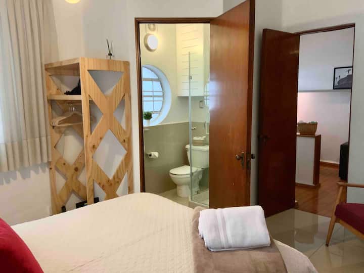 Master bedroom with queen size bed, full bathroom, armchair and closet.