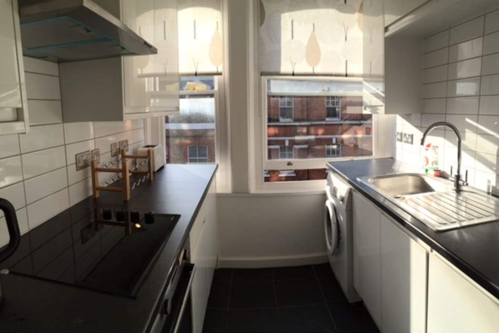 Separate modern kitchen with stovetop, fridge, dishwasher and washer/dryer.