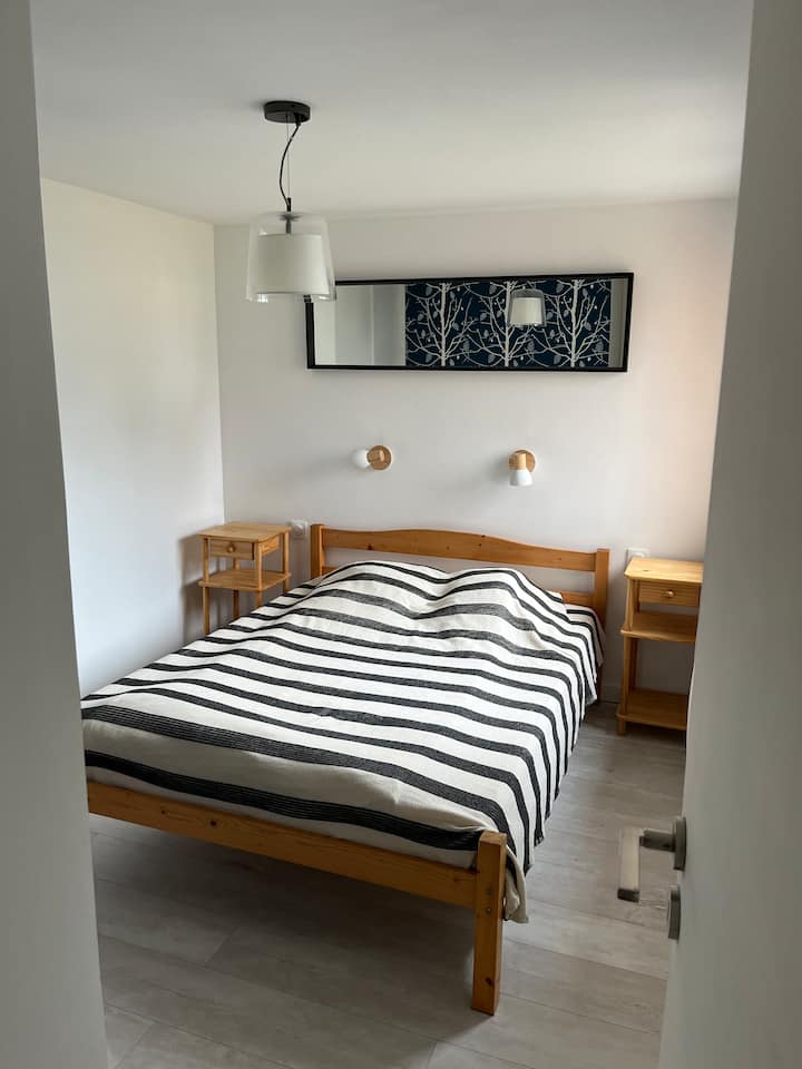 Chambre avec lit double, équipée de volets roulants électriques et placard de rangement.