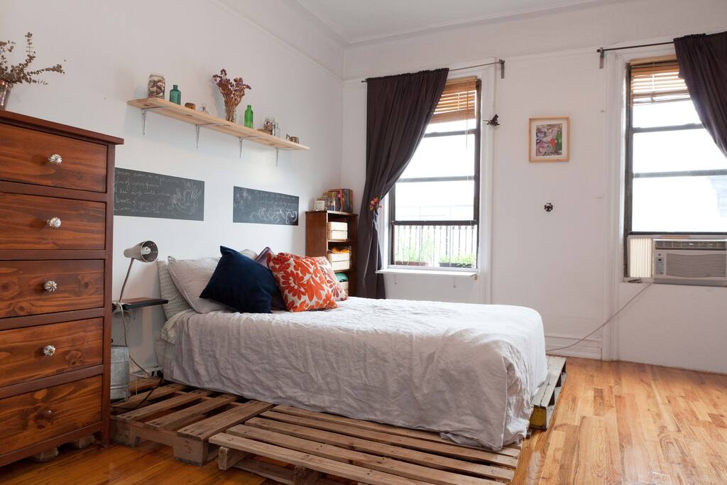Queen sized bed in room with two large windows