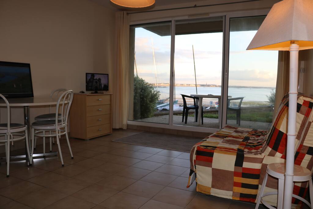 Salon avec cuisine équipée, tv, table, canapé lit et accès terrasse