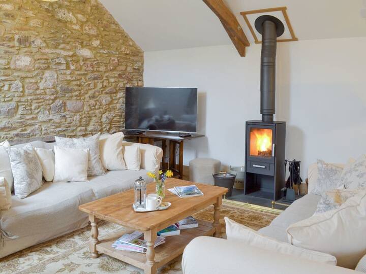 The lounge area has 2 large sofas and an arm chair surrounding the wood burner.