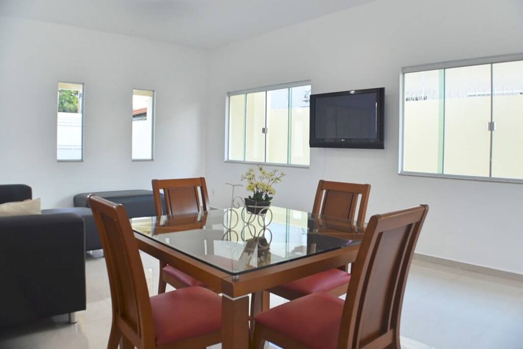 Ampla sala com TV, sofá e mesa de jantar.