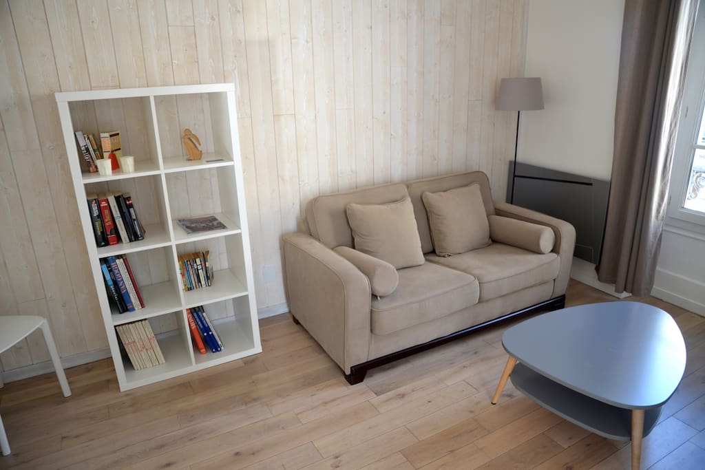 Le salon parqueté, avec le canapé, le convertible et la table base