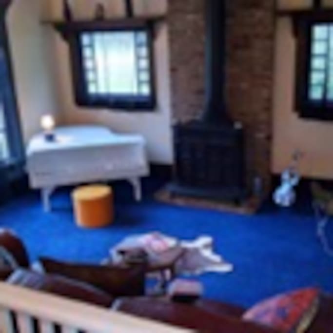 TV/sitting room wth prop piano that serves as the retro tv base (not shown); comfortable couch and stools, near to dining area.