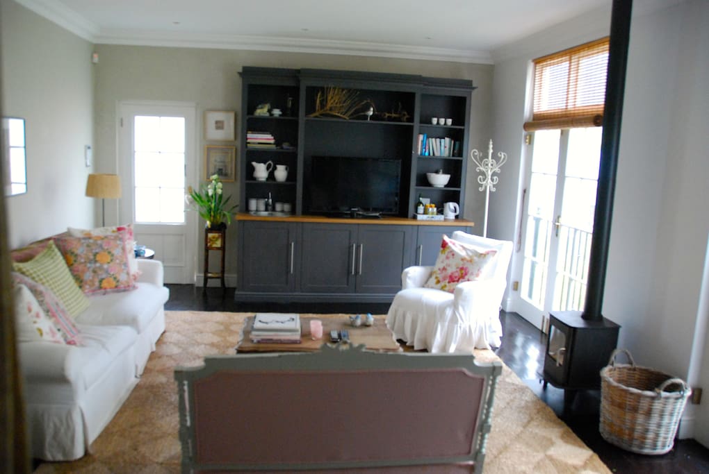 Expansive living area with flatscreen TV (with Dstv) and wood-burner fire place.
