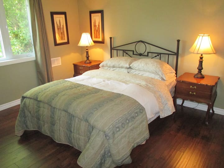 Chumba kikubwa cha kulala kina mwonekano mzuri wa bustani. Kitanda cha ukubwa wa malkia kimewekwa duvet ya chini. 