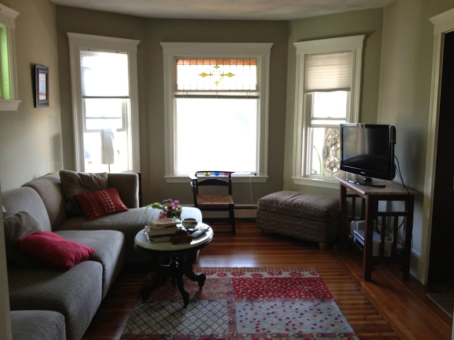 A living room with pretty windows and comfortable seating and TV.