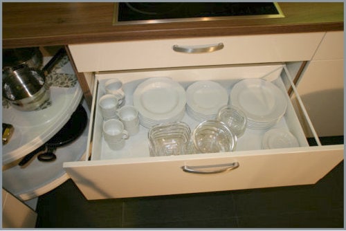 A spacious kitchen drawer is shown, containing an assortment of white plates, glass jars, and cups. The elegant arrangement showcases a well-organized kitchen space, promoting convenience and accessibility for meal preparation.