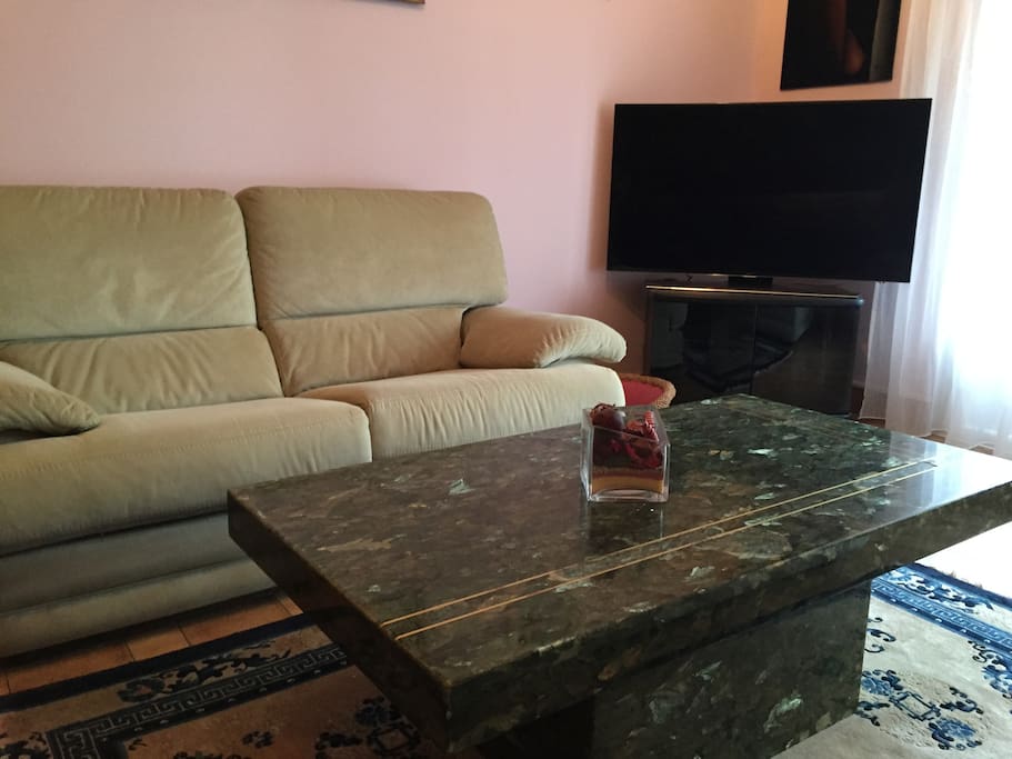 Salon lumineux avec un grand écran TV
et deux canapé.