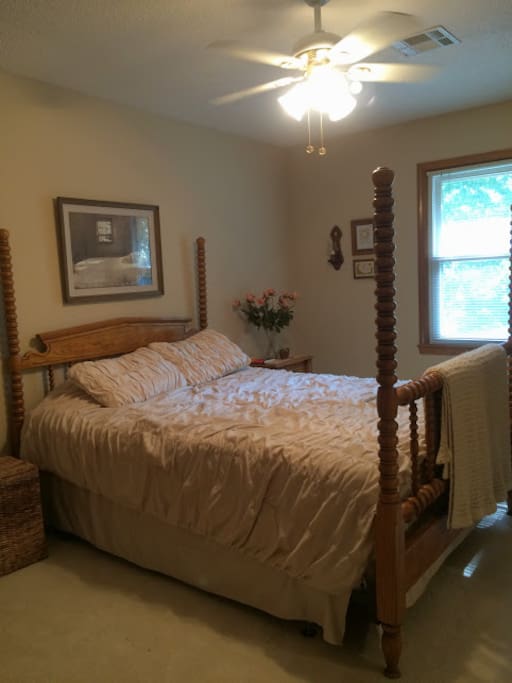 Queen-sized bed in a big bedroom with a ceiling fan; adjacent to full bath