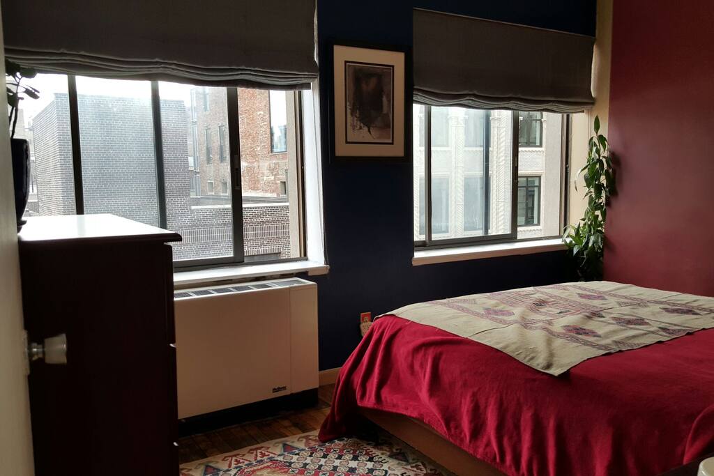 Plush queen bed with views of open sky, World Trade Center tower, and side view of Grace Church