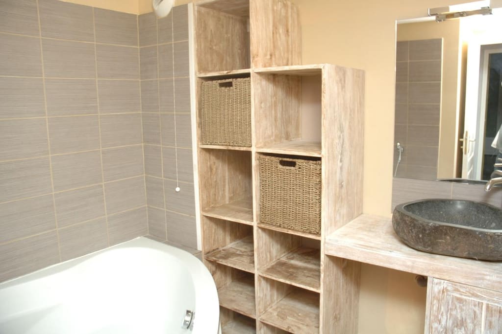 Salle de bain avec baignoire et vasque en pierre de lave.