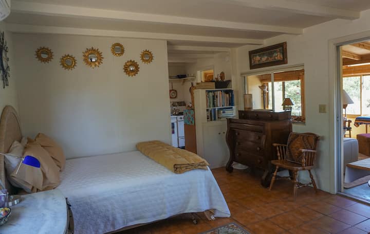 Një krevat i rehatshëm me çarçafë të butë  pambuku dhe një pamje të lindjes së diellit në mal.