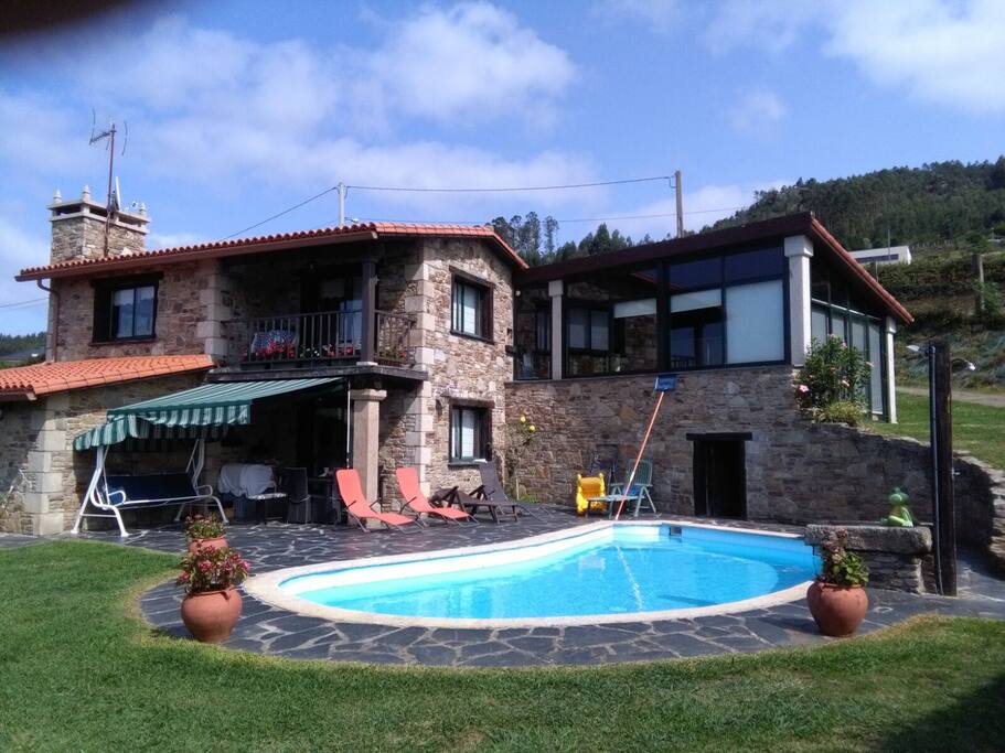 Piscina y terraza con mesa y asientos, tumbonas y balancin