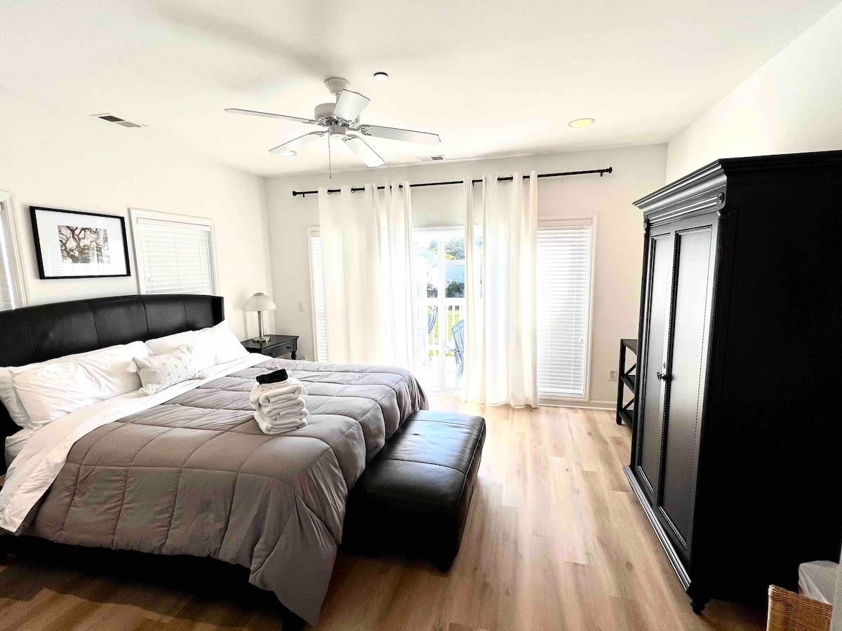 ห้องนอนใหญ่พร้อมเตียงขนาดคิงไซส์ห้องน้ำเต็มรูปแบบพร้อมฝักบัวแยกต่างหากและอ่างจากุซซี่ตู้เสื้อผ้าแบบวอล์คอินและระเบียงที่อยู่ติดกันพร้อมวิวบึงและน้ำ