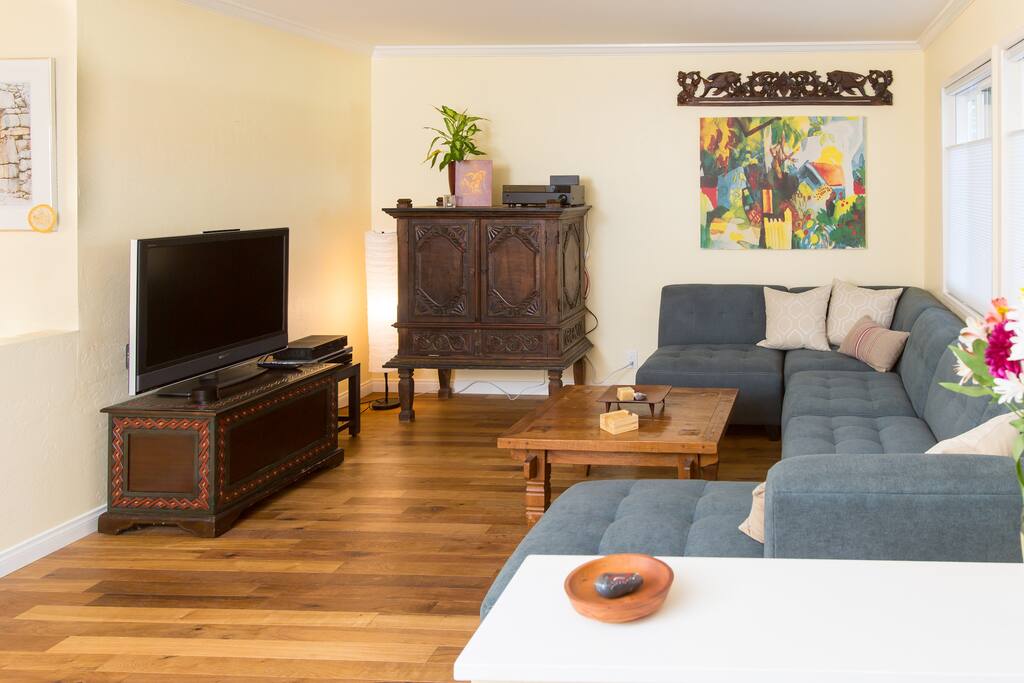 Living room with a comfortable couch, TV and cabinet with a few yoga mats inside.