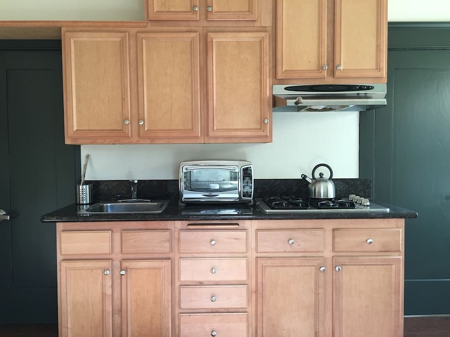 Freshly remodeled kitchen area with marble counters, stovetop, and toaster oven